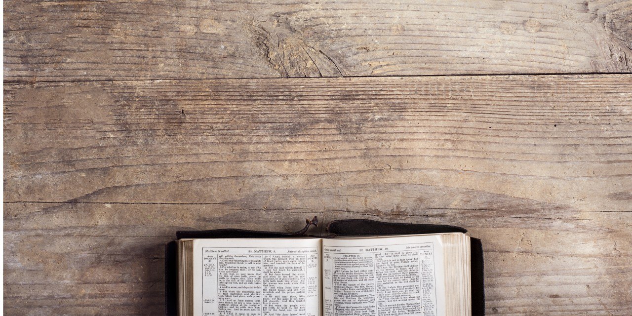 Open Bible showing the Gospel of Matthew on a rustic wooden surface